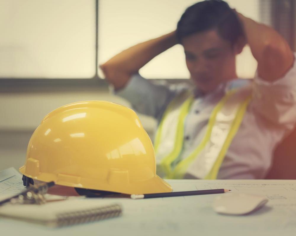 Engineer stress holding his head with hands sitting at the table in the office